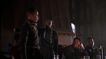 Movie still from “New Jack City” (1991), directed by Mario Van Peebles – A group of men standing next to each other in a room; Medium shot, Over the shoulder angle