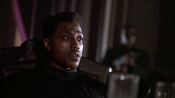 Movie still from “New Jack City” (1991), directed by Mario Van Peebles – A man sitting in front of a microphone in a room; Close Up shot, Low angle