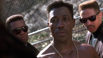 Movie still from “New Jack City” (1991), directed by Mario Van Peebles – A person wearing a necklace; Close Up shot, Over the shoulder angle