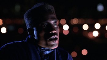 Movie still from “New Jack City” (1991), directed by Mario Van Peebles – A man in a blue jacket is looking at the camera; Close Up shot, Low angle