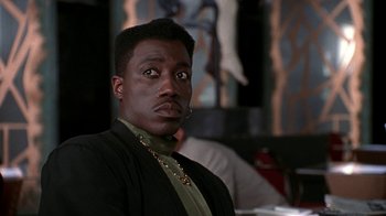 Movie still from “New Jack City” (1991), directed by Mario Van Peebles – A person wearing a suit and tie; Close Up shot, Low angle