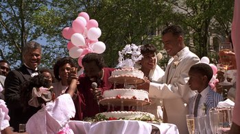 Movie still from “New Jack City” (1991), directed by Mario Van Peebles – A group of people standing next to a cake; Medium shot, High angle