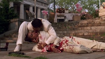Movie still from “New Jack City” (1991), directed by Mario Van Peebles – Two people are laying on the ground with blood on them; Medium shot, High angle