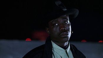 Movie still from “New Jack City” (1991), directed by Mario Van Peebles – A man wearing a black hat and a white shirt; Close Up shot, Low angle