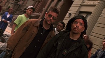 Movie still from “New Jack City” (1991), directed by Mario Van Peebles – A group of men standing next to each other on the street; Medium shot, Low angle