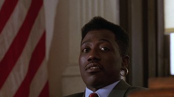 Movie still from “New Jack City” (1991), directed by Mario Van Peebles – A person wearing a suit and tie; Close Up shot, Low angle