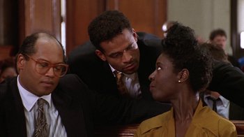 Movie still from “New Jack City” (1991), directed by Mario Van Peebles – Two men and a woman are sitting in a room; Close Up shot, Over the shoulder angle