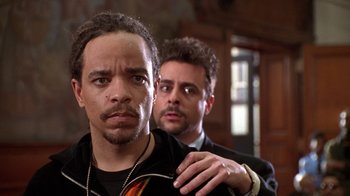 Movie still from “New Jack City” (1991), directed by Mario Van Peebles – Two men in black suits are standing next to each other; Close Up shot, Low angle