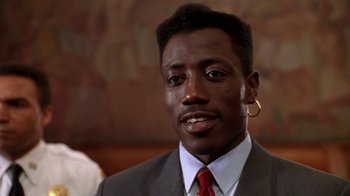 Movie still from “New Jack City” (1991), directed by Mario Van Peebles – A person wearing a suit and tie; Close Up shot, Low angle