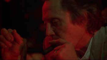 Movie still from “New Rose Hotel” (1998), directed by Abel Ferrara – A person smoking a cigar; Close Up shot, Over the shoulder angle