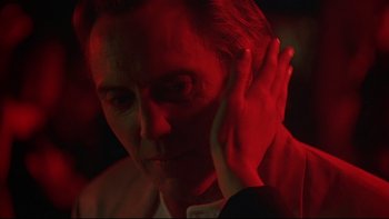 Movie still from “New Rose Hotel” (1998), directed by Abel Ferrara – A man with his hand up to his ear; Close Up shot, Over the shoulder angle