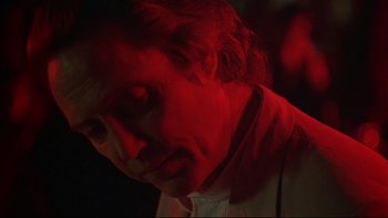 Movie still from “New Rose Hotel” (1998), directed by Abel Ferrara – A man in a white shirt and a red light; Close Up shot, Over the shoulder angle