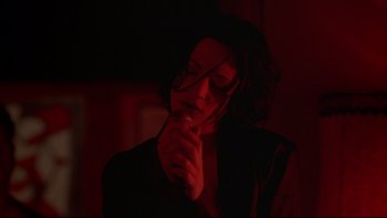 Movie still from “New Rose Hotel” (1998), directed by Abel Ferrara – A woman in a dark room holding a microphone; Close Up shot, Low angle