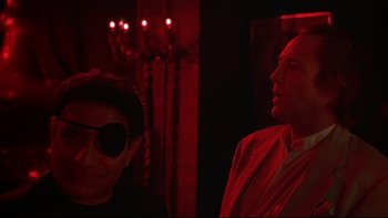 Movie still from “New Rose Hotel” (1998), directed by Abel Ferrara – A man and a woman standing next to each other in a room; Medium shot, Over the shoulder angle