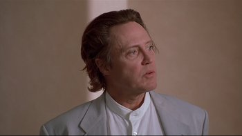 Movie still from “New Rose Hotel” (1998), directed by Abel Ferrara – A person wearing a suit and tie; Close Up shot, Low angle
