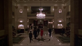 Movie still from “New Rose Hotel” (1998), directed by Abel Ferrara – A group of people walking around a lobby; Extreme Wide shot, High angle