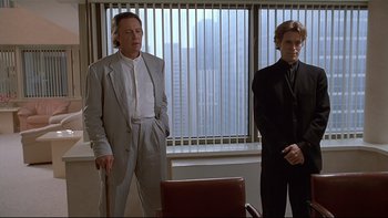 Movie still from “New Rose Hotel” (1998), directed by Abel Ferrara – Two men in suits standing in front of an office window; Medium shot, Low angle