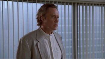 Movie still from “New Rose Hotel” (1998), directed by Abel Ferrara – A person wearing a suit and tie; Close Up shot, Low angle