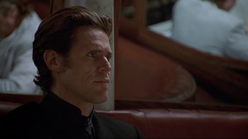 Movie still from “New Rose Hotel” (1998), directed by Abel Ferrara – A person wearing a suit and tie; Close Up shot, Low angle