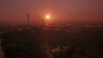 Movie still from “New Rose Hotel” (1998), directed by Abel Ferrara – The sun is setting over a large body of water; Extreme Wide shot, High angle