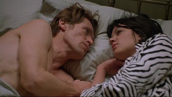 Movie still from “New Rose Hotel” (1998), directed by Abel Ferrara – A man and a woman laying in a bed together; Close Up shot, Overhead angle