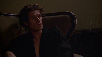 Movie still from “New Rose Hotel” (1998), directed by Abel Ferrara – A man sitting in a chair looking up at the sky; Close Up shot, Low angle