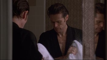 Movie still from “New Rose Hotel” (1998), directed by Abel Ferrara – A man in a black robe looking in the mirror; Close Up shot, Low angle