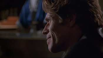 Movie still from “New Rose Hotel” (1998), directed by Abel Ferrara – A man's face in a dark room; Close Up shot, Over the shoulder angle