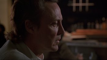 Movie still from “New Rose Hotel” (1998), directed by Abel Ferrara – A man's face in a dark room; Close Up shot, Low angle