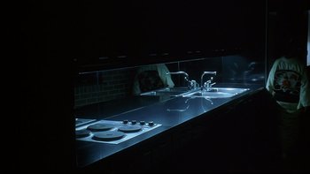 Movie still from “New Rose Hotel” (1998), directed by Abel Ferrara – A kitchen sink and a counter with lights on it; Wide shot, High angle