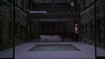 Movie still from “New Rose Hotel” (1998), directed by Abel Ferrara – A woman standing in front of a pool of water; Wide shot, Low angle
