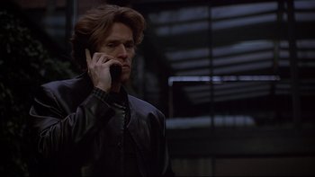 Movie still from “New Rose Hotel” (1998), directed by Abel Ferrara – A man in a leather jacket talking on a cell phone; Medium shot, Low angle