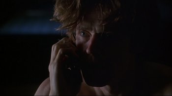 Movie still from “New Rose Hotel” (1998), directed by Abel Ferrara – A man talking on a cell phone in the dark; Close Up shot, Low angle