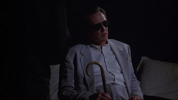 Movie still from “New Rose Hotel” (1998), directed by Abel Ferrara – A man in a white suit holding an umbrella; Medium shot, Low angle