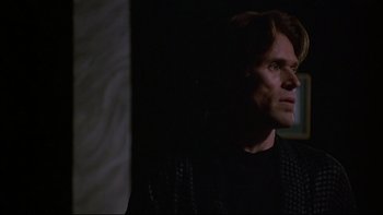Movie still from “New Rose Hotel” (1998), directed by Abel Ferrara – A man in a black shirt looking up at the ceiling; Close Up shot, Low angle
