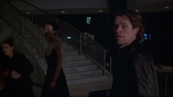 Movie still from “New Rose Hotel” (1998), directed by Abel Ferrara – A man and a woman walking down a set of stairs; Medium shot, Low angle