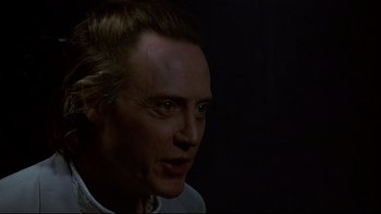 Movie still from “New Rose Hotel” (1998), directed by Abel Ferrara – A person in a dark room; Close Up shot, Over the shoulder angle