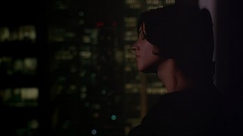 Movie still from “New Rose Hotel” (1998), directed by Abel Ferrara – A woman standing in front of a city skyline at night; Close Up shot, Low angle