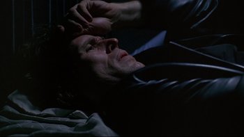 Movie still from “New Rose Hotel” (1998), directed by Abel Ferrara – A man laying on the ground with his eyes closed; Close Up shot, Overhead angle