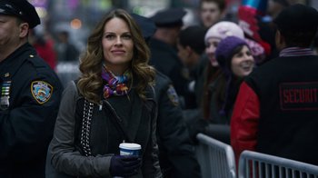Movie still from “New Year's Eve” (2011), directed by Garry Marshall – A woman holding a cup of coffee while standing next to a crowd of onlookers; Close Up shot, Over the shoulder angle