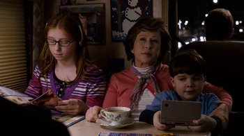 Movie still from “New Year's Eve” (2011), directed by Garry Marshall – A woman and two children sitting at a table; Medium shot, Over the shoulder angle