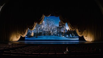 Movie still from “New Year's Eve” (2011), directed by Garry Marshall – A man sitting in a theater looking out at a snowy scene; Extreme Wide shot, High angle