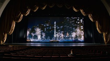 Movie still from “New Year's Eve” (2011), directed by Garry Marshall – A man sitting in front of a large screen in a theater; Extreme Wide shot, High angle