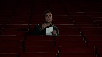 Movie still from “New Year's Eve” (2011), directed by Garry Marshall – A man is sitting in a row of red seats; Wide shot, High angle