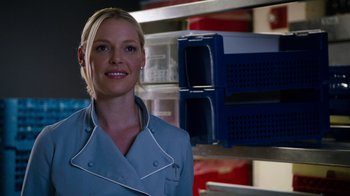 Movie still from “New Year's Eve” (2011), directed by Garry Marshall – A woman standing in front of a shelf with many items; Close Up shot, Over the shoulder angle