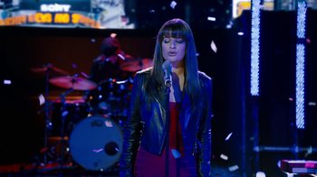 Movie still from “New Year's Eve” (2011), directed by Garry Marshall – A woman in a black jacket is singing; Medium shot, Low angle