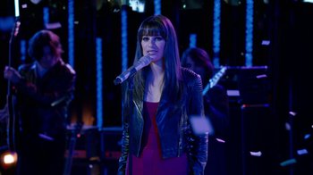 Movie still from “New Year's Eve” (2011), directed by Garry Marshall – A woman in a black leather jacket holding a microphone; Medium shot, Over the shoulder angle