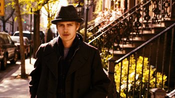 Movie still from “New York, I Love You” (2008), directed by Wen Jiang – A young man in a hat and a coat standing in front of stairs; Medium shot, Low angle