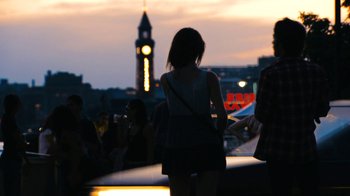 Movie still from “New York, I Love You” (2008), directed by Wen Jiang – A woman standing in front of a clock tower at night; Wide shot, Over the shoulder angle