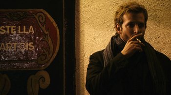Movie still from “New York, I Love You” (2008), directed by Wen Jiang – A young man standing next to a wall eating something; Medium shot, Over the shoulder angle